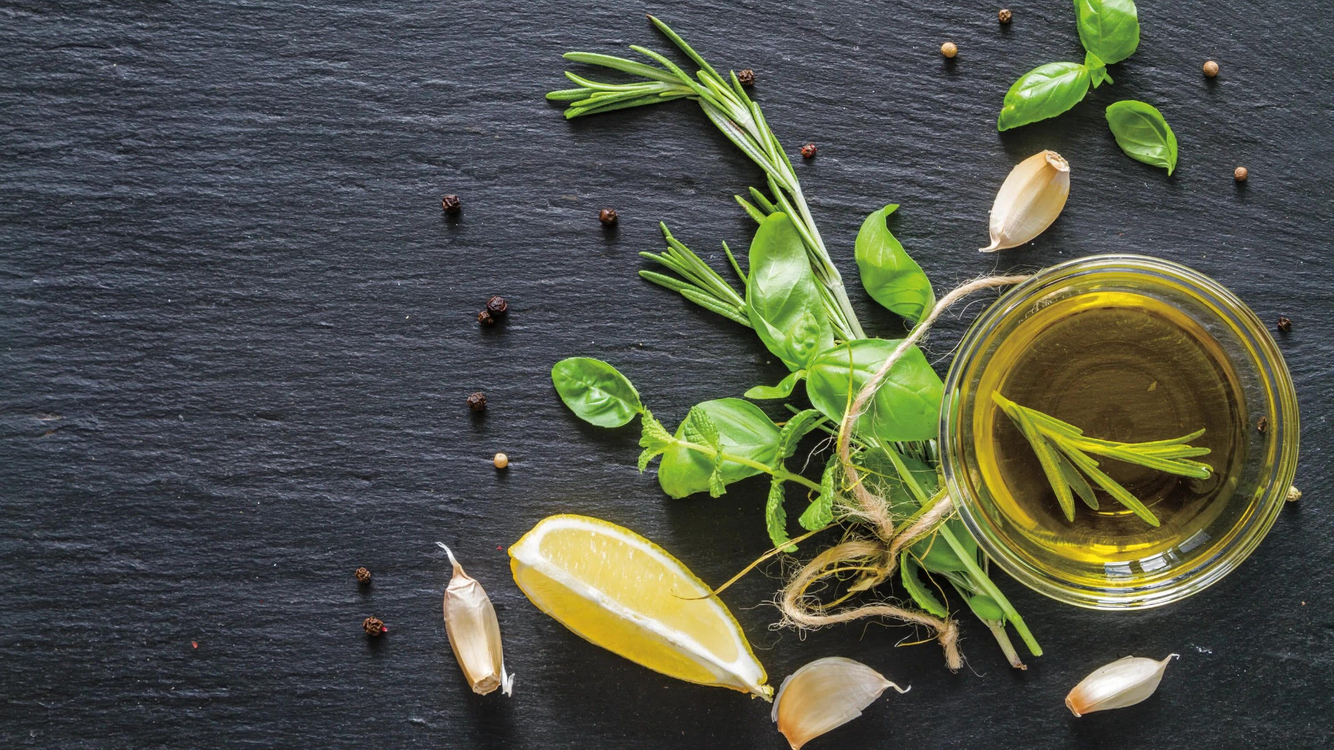 oil in a glass cup with herbs and lemon